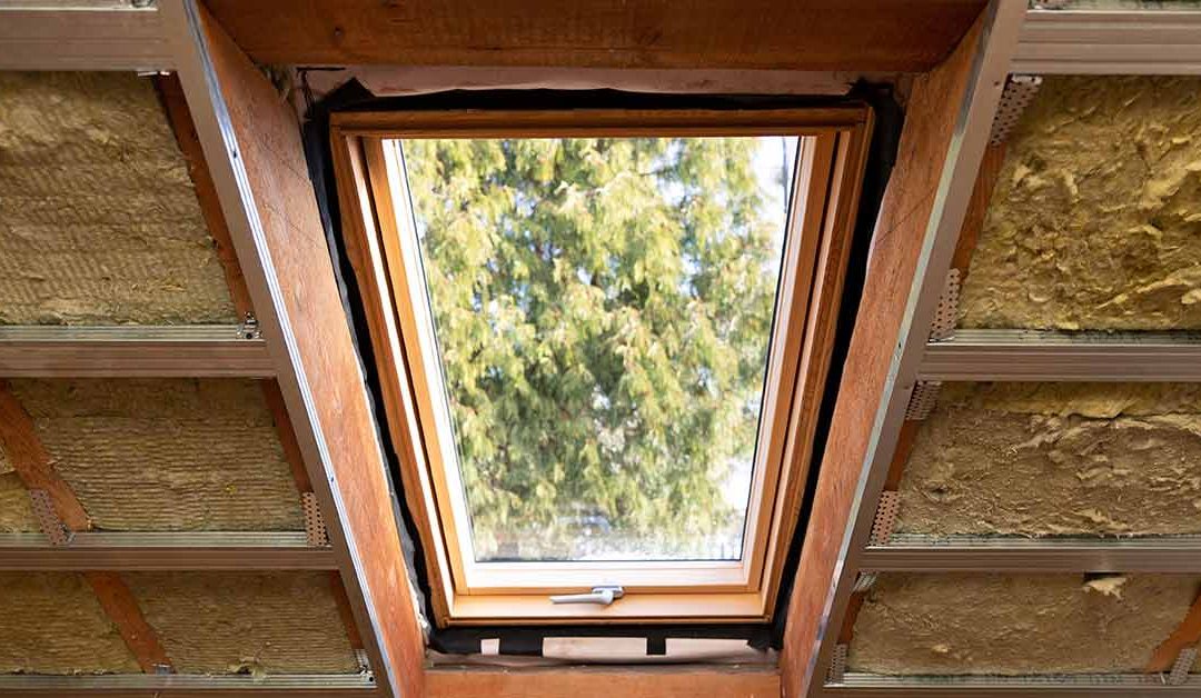 Ein Dachfenster, bei dem ringsherum Glaswolle zur Dämmung des Dachstuhls zu sehen ist.| Neue EU-Gebäuderichtlinie