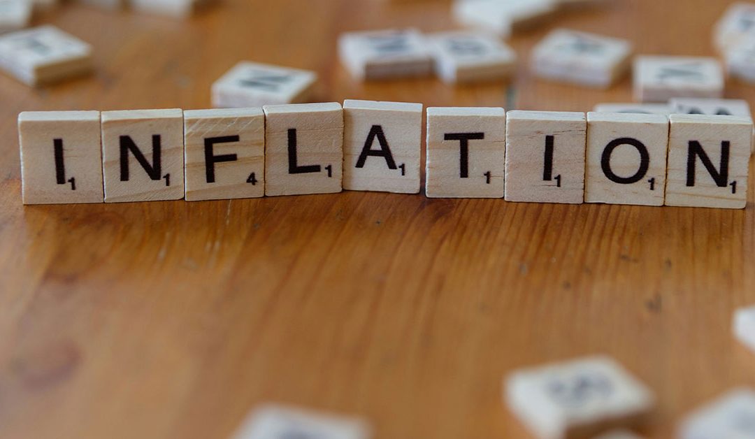 Auf einem Tisch liegt aus Scrabble-Buchstaben gelegt das Wort "Inflation" als Symbol für Immobilieninvestments während einer Inflation | Immobilieninvestment