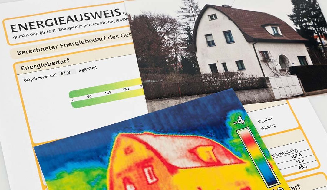 Ein Energieausweis liegt neben zwei Bildern von Häusern. Das eine ist ein realistisches Foto, das andere stellt das Gebäude als Wärmebild dar.
